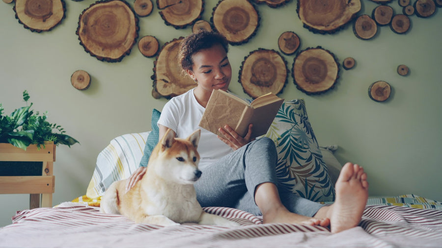 Chica leyendo en la cama junto a su perro